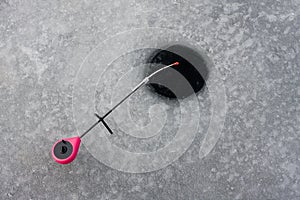 Winter ice fishing. Fishing rod is on ice near hole. Balalaika rod is popular type of rod for ice-fishing photo