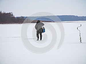 Winter ice fishing, lake, frosty day. fisherman collects gear