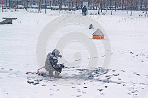 Winter ice fishing, lake, frosty day. Fisherman engaged in ice fishing in the pond of the city Park