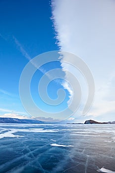 Winter ice landscape on lake Baikal with dramatic weather clouds