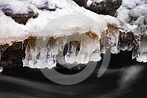 Winter icicles above stream. Frozen water with bubble