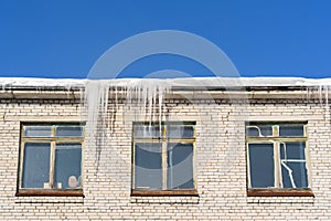 In the winter icicles are hanging on a building roof