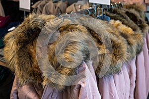 Winter jackets with fur collars hanging on plastic hangers in a store