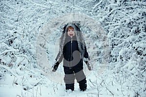 Winter kid posing and having fun. Winter portrait of cute child in snow Garden. Winter landscape of forest and snow with