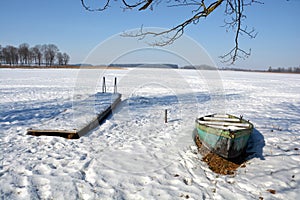 Winter lake landscape with old wooden boat and pier