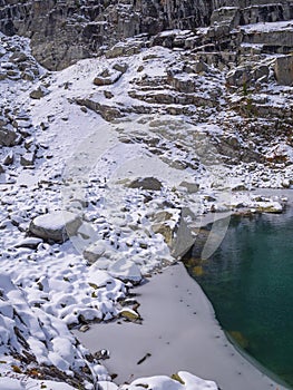 Winter lake rocky shore covered by fresh snow