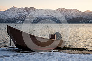 Winter landscape around Lake Skadar, Montenegro: boat on the shores and snowcapped mountains