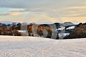 Horská zimná krajina pred západom slnka. Posledné lúče slnka ožiarili stromy a les v údolí