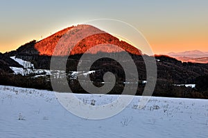 Winter landscape. Beautifully illuminated mountain hill at sunset. With shadows. 