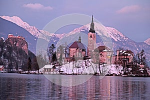 Winter landscape of Bled Lake and island church on sunset
