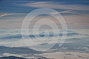 Winter landscape with blue mountain ridges and hazy valleys