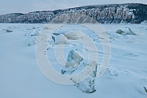 Winter landscape in blue tones with ridged ice on the frozen river at twilight