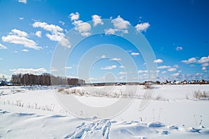 Winter landscape. Countryside. Frozen river. Sunny day. Blue sky. White clouds