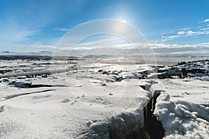 Winter landscape , cracked snow covered ground with the sun on blue sky, at Pingvellir national park in Iceland