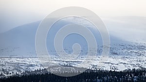 Winter landscape with foggy snowy mountains