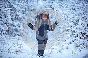 Winter landscape of forest and snow with cute child boy. Kids having fun in white snow field against snowy trees. People