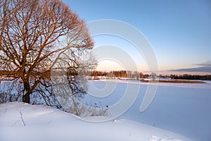 Winter landscape on frosty sunny day. Frozen river under snow