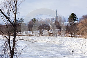 Winter landscape with frozen Cap-Rouge river and pretty small 1859 stone Saint-Felix-de-Valois church