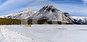 Winter landscape of the frozen Lake Minnewanka surrounded by the