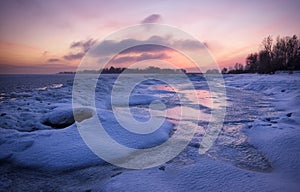 Winter landscape with frozen lake and sunset sky.