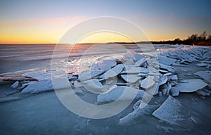 Winter landscape with frozen lake and sunset sky.