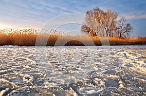 Winter landscape with frozen river and sunset sky