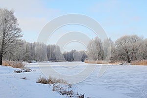 Winter landscape with frozen river and trees covered with snow