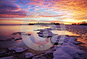 Winter landscape with lake and sunset fiery sky.