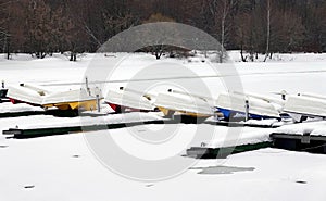 WInter landscape with many overturned boats in the snow on a pier on a frozen river