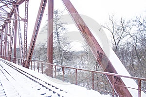 Winter landscape. Metall red bridge over the frozen river. photo