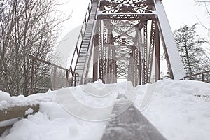 Winter landscape. Metall red bridge over the frozen river. photo