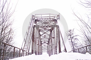 Winter landscape. Metall red bridge over the frozen river. photo