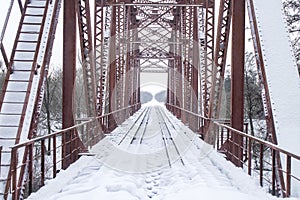 Winter landscape. Metall red bridge over the frozen river. photo