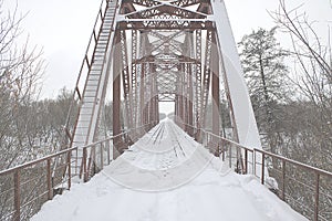 Winter landscape. Metall red bridge over the frozen river. photo