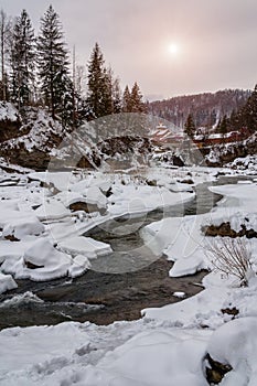 Winter landscape. Mountain river flows from the rocks. Snow and mountain river