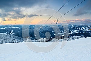 Winter landscape in the mountains on ski resort near chairlift on sunset. Snow covered hills after heavy snowfall. Snowy