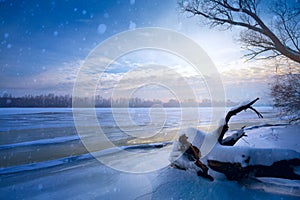 winter landscape panorama; sunset on the bank of a frozen river; ice and snow