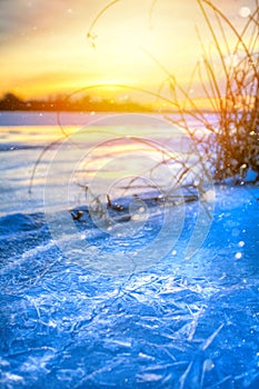 winter landscape panorama; sunset on the bank of a frozen river; ice and snow