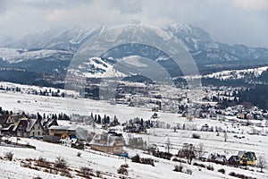 Winter Landscape Of Poland Tatra Mountains. Snow-covered Valley With Many Traditional Polish Houses At The Background Of Snow-Capp