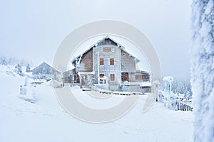 Winter landscape in the Polish mountains of the Sudetes, a snow-capped mountain shelter on a hiking trail on a cloudy, foggy day