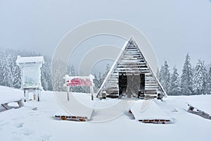 Winter landscape in the Polish mountains of the Sudetes, snow-covered tourist shelter on a mountain hiking trail, thick snow cover