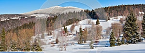 Winter landscape in the Polish mountains of the Sudetes, a sunny day on a snow-covered trail in the mountains with a panorama