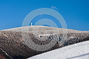 Winter landscape in the Polish mountains of the Sudetes, a view of the snow-capped mountain peaks, an observation tower on the top