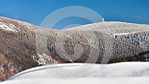 Winter landscape in the Polish mountains of the Sudetes, a view of the snow-capped mountain peaks, an observation tower on the top