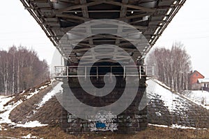 Winter landscape with railroad bridge over frozen river, snow-covered trees, hoarfrost