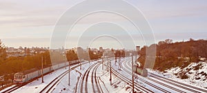 Winter landscape with a railway train on a railway surrounded by a city panorama with lots of houses and buildings against a clou