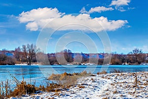 Winter landscape with a river and a beautiful white cloud in the blue sky