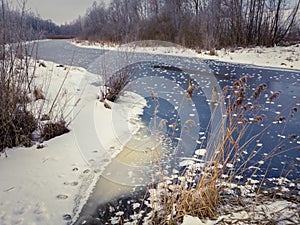 Winter landscape with river covered with ice and frost.