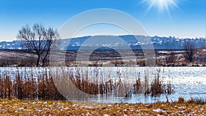 Winter landscape with river and field in sunny weather