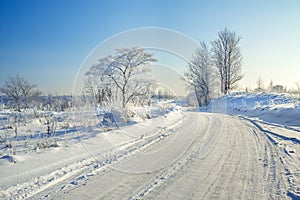 Winter landscape with the road, forest and the blue sky